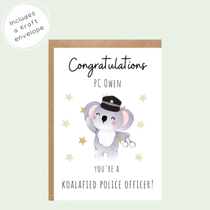 A congratulations card for a police officer, featuring a cute cartoon koala dressed as a police officer with handcuffs. The card is white with black text and gold star accents, shown with a brown kraft envelope.